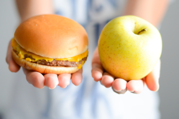 Mains présentant d'un coté un burger et de l'autre une pomme